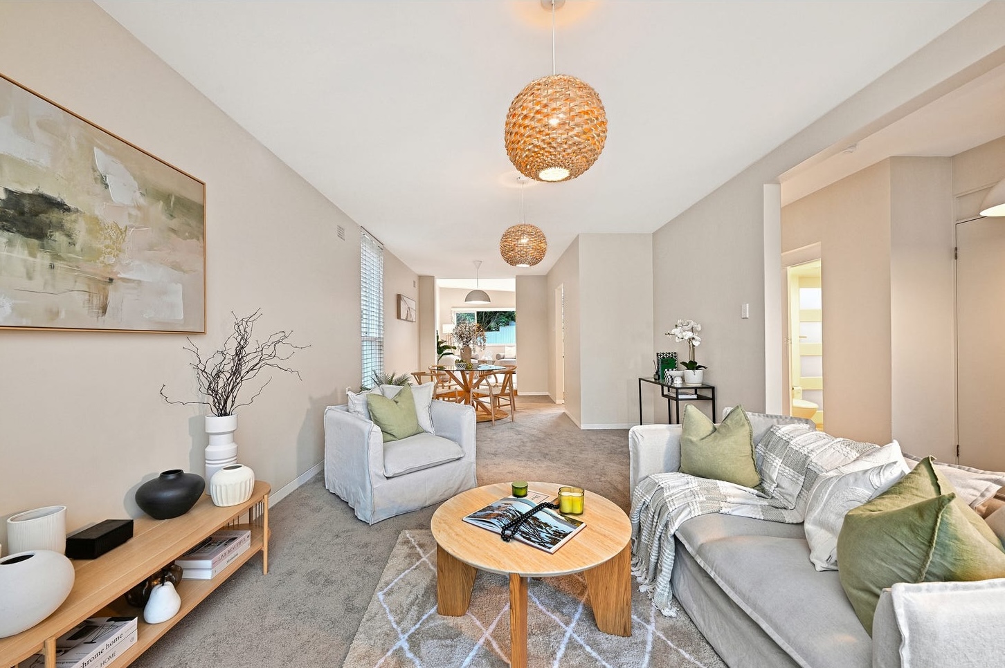 Long view through the staged house from the front living room past the armchair to the dining room