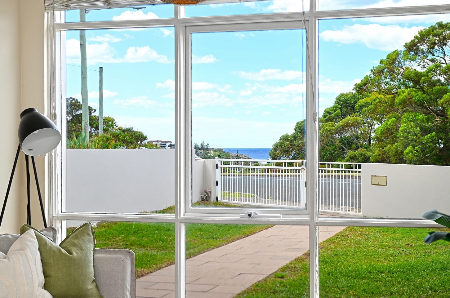 View from the front living room through floor-to-ceiling glass to the lawn, Arthur Byrne Reserve and the ocean